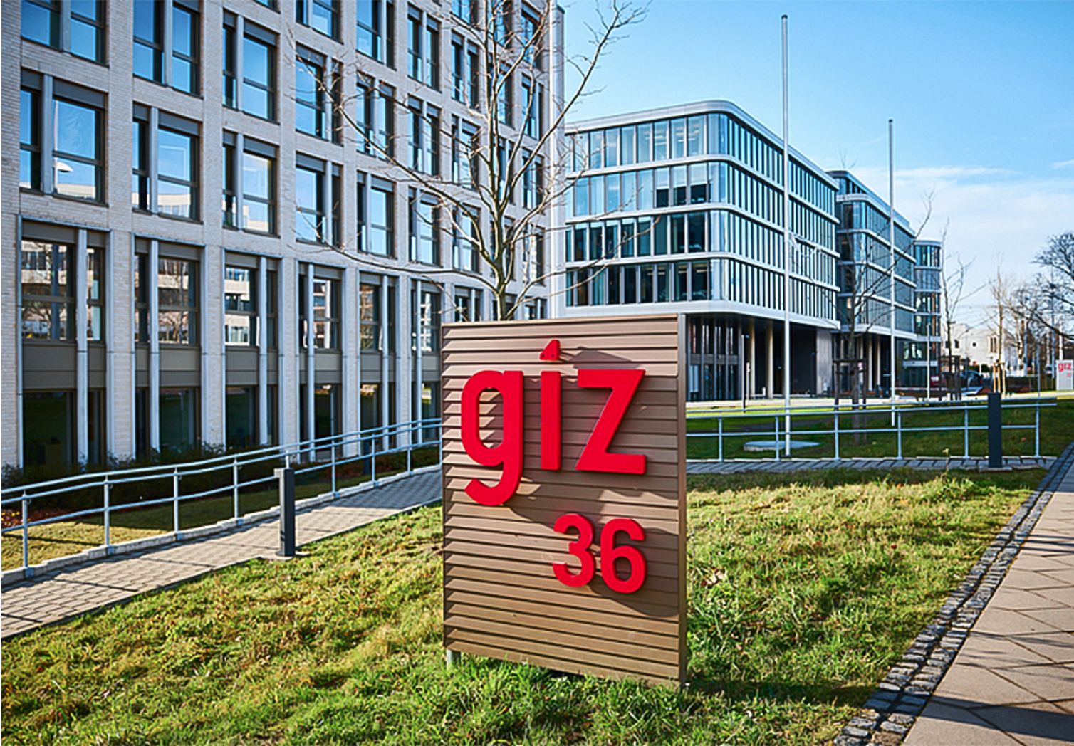 Foto: Vor mehreren modernen Gebäuden steht ein Schild mit dem GIZ-Logo.